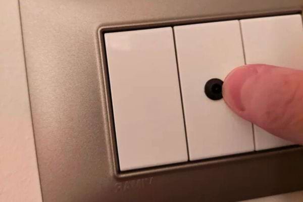 Interrupteur avec une petite lentille noire ressemblant à une caméra cachée.