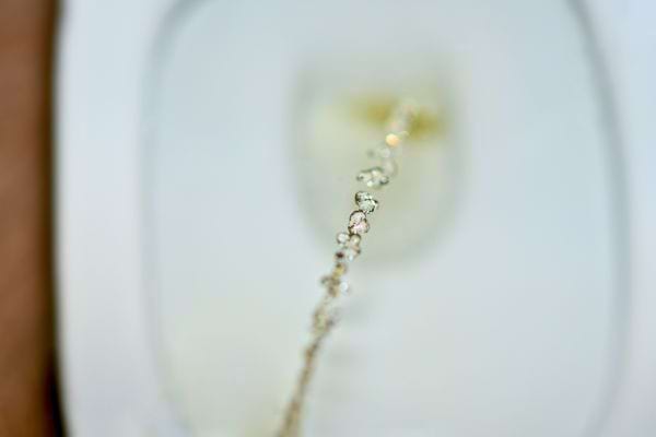 Jet d’urine capturé en gros plan au-dessus de la cuvette.