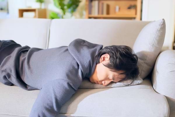 Homme allongé sur un canapé, endormi en pleine journée.