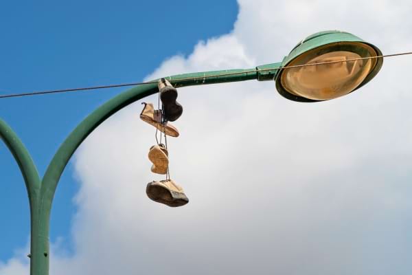 Plusieurs paires de baskets accrochées à un câble sur un lampadaire.