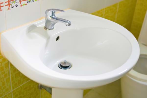 Lavabo blanc propre, prêt à être utilisé dans une salle de bain carrelée en jaune.