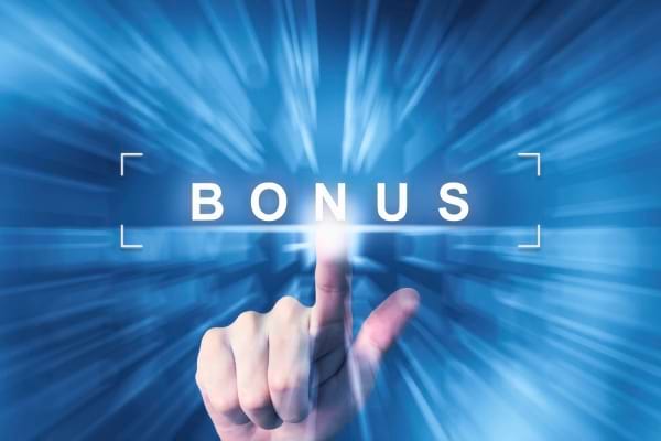 Une main appuie sur un bouton lumineux affichant le mot BONUS sur fond bleu flou.