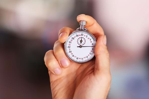 Une main tient un chronomètre affichant une durée très courte, en gros plan.