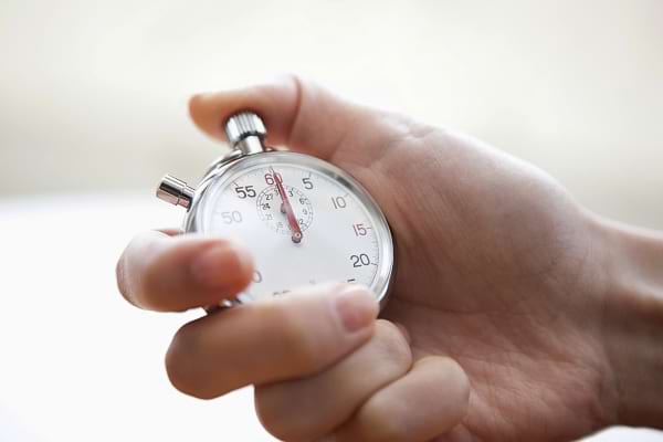 Une main tient un chronomètre prêt à être déclenché.