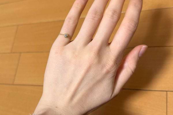 Main fine avec une bague discrète au petit doigt.