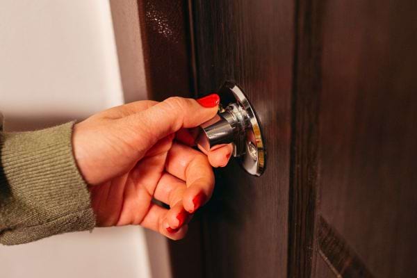 Main féminine verrouille une porte avec un loquet.