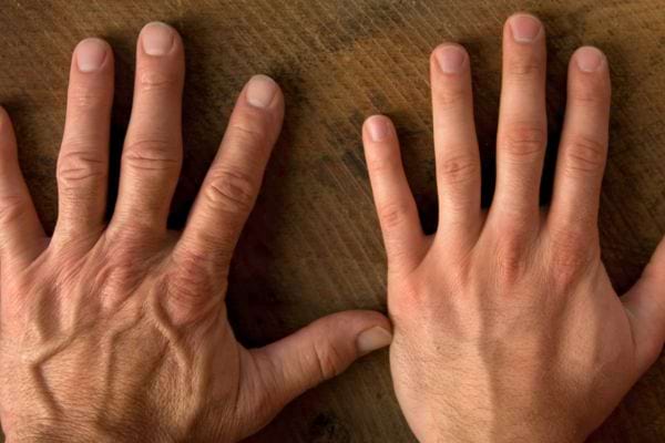 Deux mains masculines posées à plat sur une surface en bois.