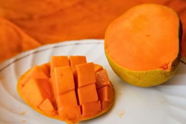 Une mangue découpée en cubes et une moitié entière.