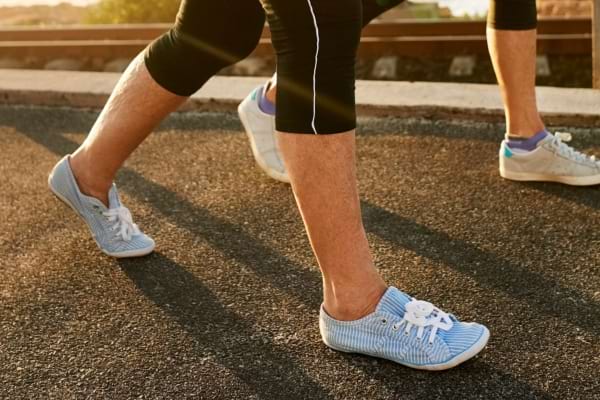 Deux personnes marchant à reculons sur une route en plein air, lumière dorée de fin de journée. 