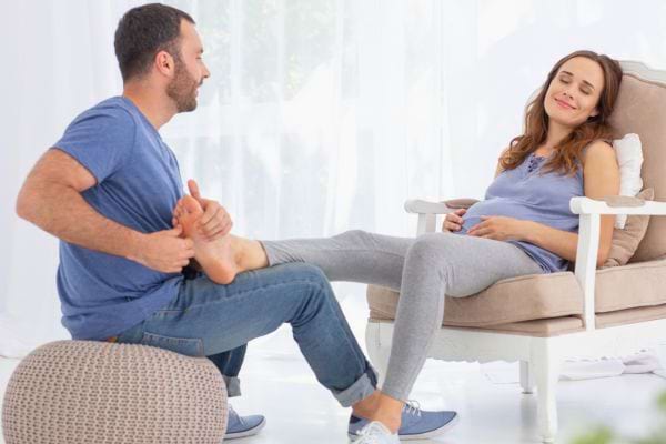 Un homme masse les pieds de sa compagne enceinte.