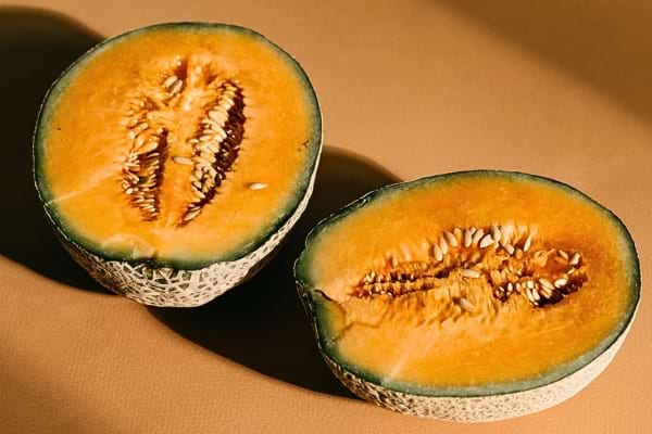 Un melon bien mûr coupé en deux, chair orange éclatante.