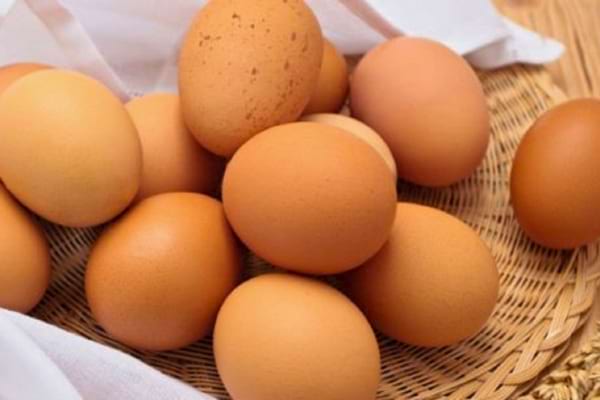 Oeufs bruns entiers dans un panier tressé avec un tissu blanc.