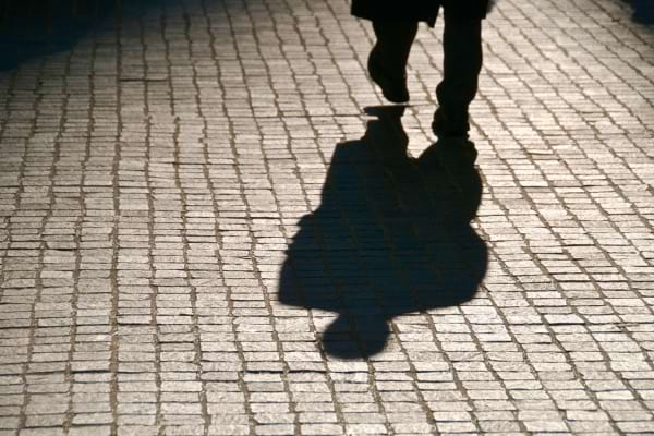 L’ombre d’un homme marchant sur un sol pavé au coucher du soleil.