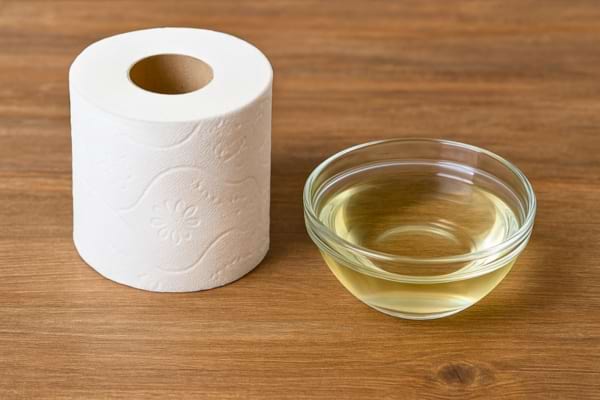 Rouleau de papier toilette posé à côté d’un bol rempli de vinaigre transparent.