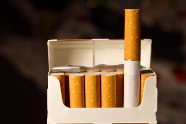 Paquet de cigarettes ouvert avec une cigarette dépassant, illustrant un danger connu pour la santé.