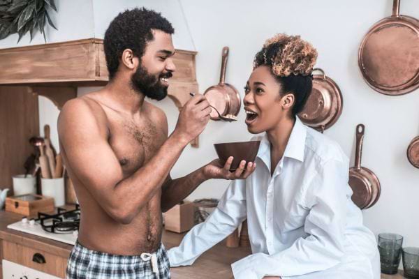 Il nourrit sa partenaire avec amour dans la cuisine.