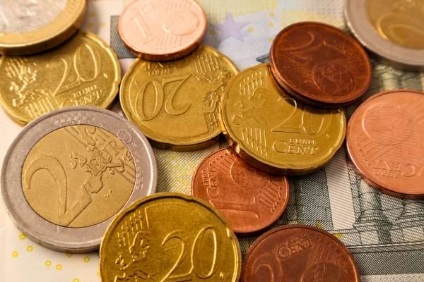 Plusieurs pièces en euros de différentes valeurs posées sur un billet, illustrant des économies ou un budget.