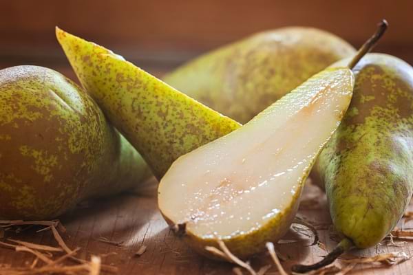 Des poires vertes juteuses, dont une est découpée.