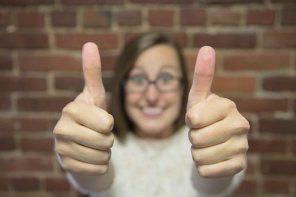 Une femme souriante fait un double pouce levé en signe d’approbation.