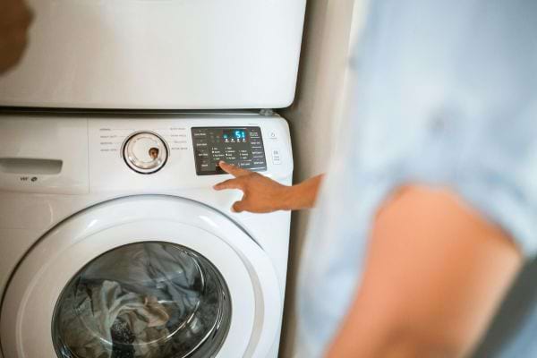 Une personne règle le programme d'une machine à laver moderne.