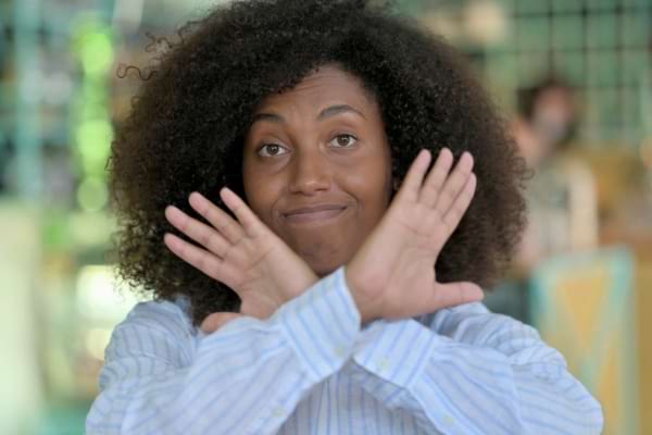 Femme faisant un geste de refus avec ses bras croisés devant elle.