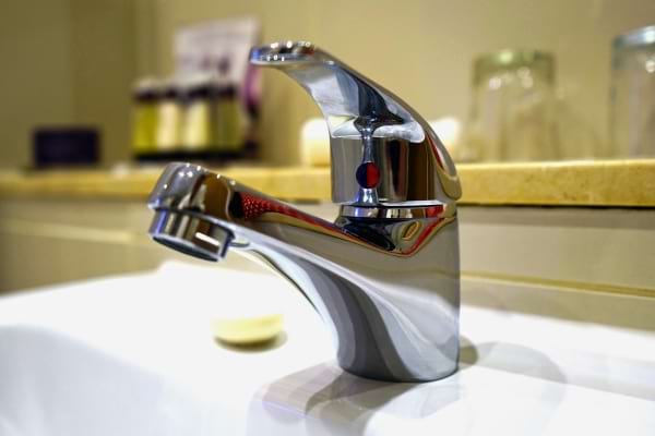 Gros plan sur un robinet fermé brillant dans une salle de bain moderne, suggérant la sobriété.