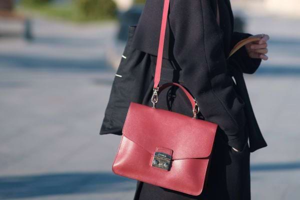 Personne en manteau noir avec sac &agrave; bandouli&egrave;re rouge.