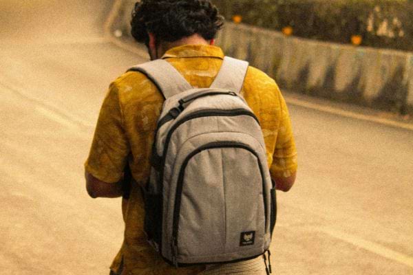 Homme de dos marchant avec un sac &agrave; dos gris.