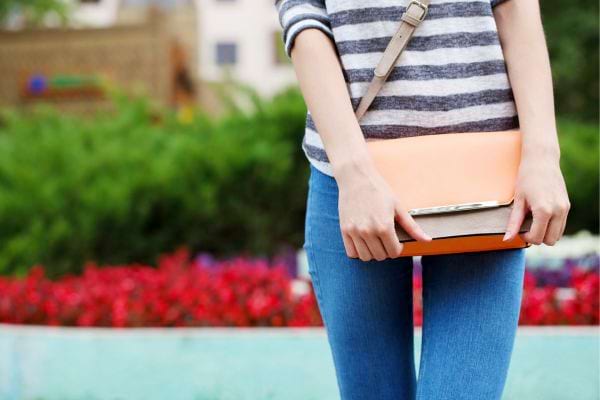 Personne tenant un sac pochette contre elle avec deux mains.