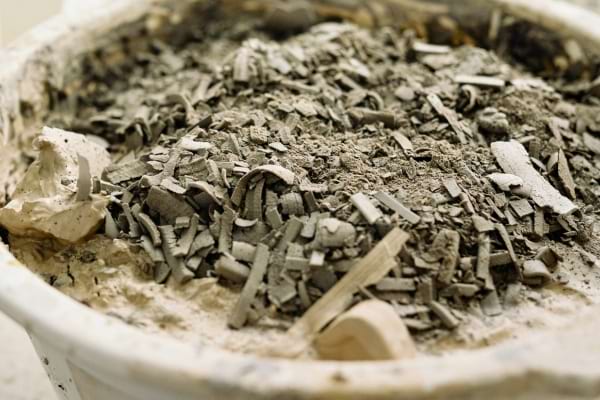 Un seau blanc rempli de cendres de bois grises.