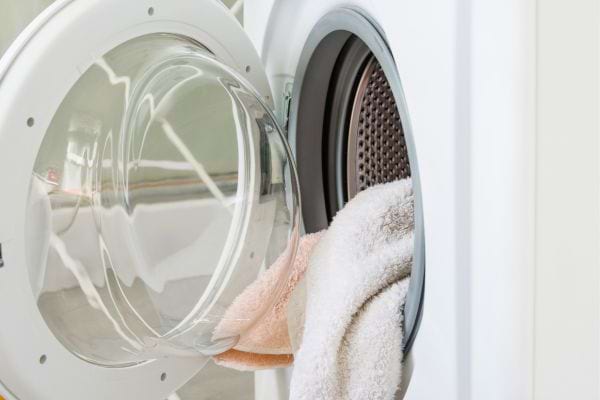 Des serviettes dépassent d'une machine à laver ouverte.