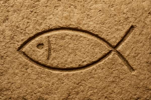 Poisson chrétien gravé dans une pierre de couleur sable.