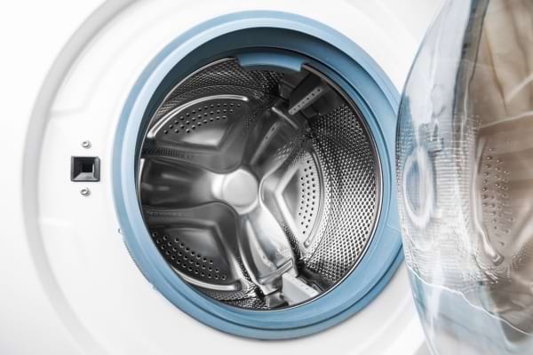 Gros plan sur le tambour propre et vide d’une machine à laver ouverte.