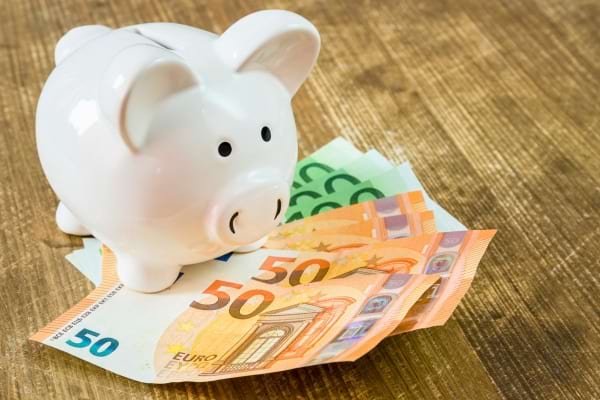 Une tirelire blanche posée sur des billets d’euros de 50 et 100, symbole d’économies.