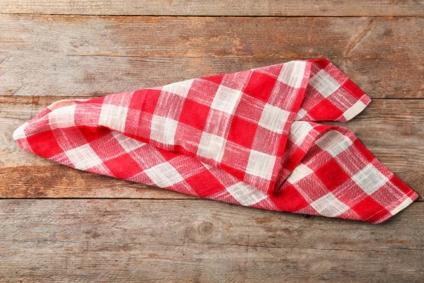 Un torchon à carreaux rouges et blancs est posé sur une table en bois rustique.