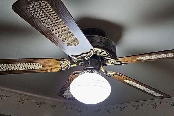 Ventilateur rétro à cinq pales en bois avec lumière centrale blanche.