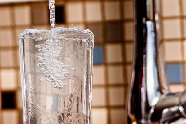 Un verre se remplit d’eau claire au robinet.