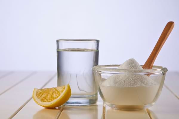Un citron, un verre d’eau et un bol de bicarbonate forment un trio de nettoyage naturel.