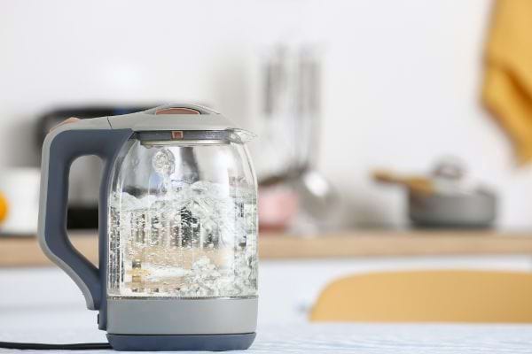 Bouilloire électrique transparente chauffant de l’eau sur une table de cuisine.