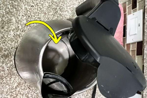 Intérieur d’une bouilloire montrant des dépôts de calcaire avec une flèche jaune.