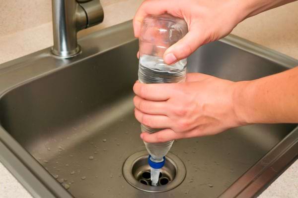 Une bouteille d’eau est pressée à l’envers pour envoyer l’eau dans le siphon.