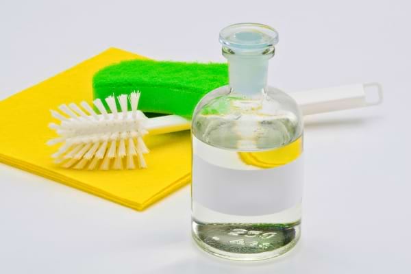 Bouteille de vinaigre avec éponge et brosse.