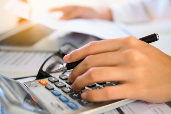 Main utilisant une calculatrice avec un stylo.