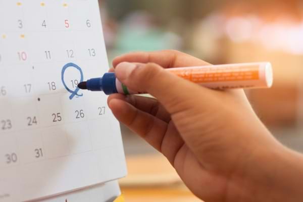 Une main qui entoure une date sur un calendrier.