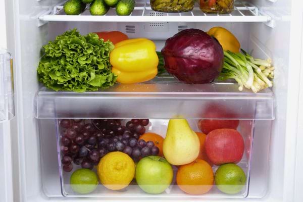 vUn bac de frigo avec raisins, poires, pommes, agrumes et légumes frais colorés.