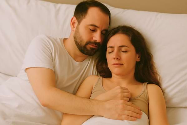 Couple allongé, l’homme enlace une femme les yeux fermés.