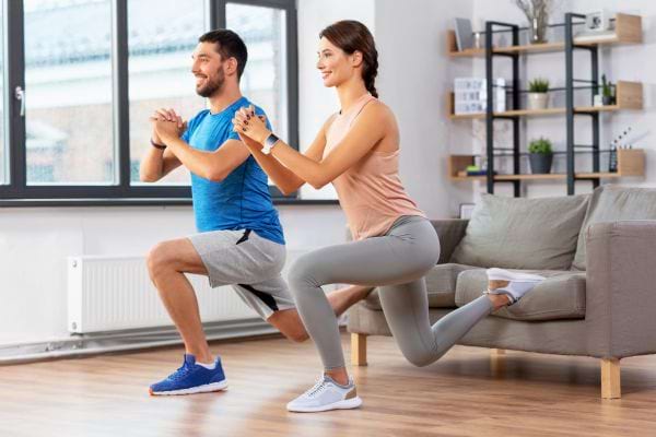 Un couple fait des exercices de sport ensemble dans le salon.