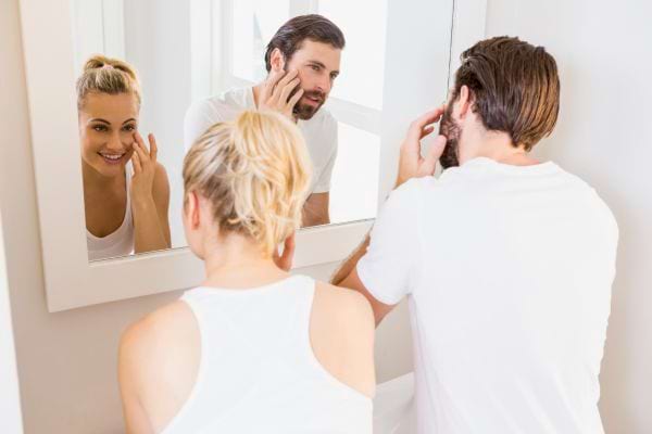Couple se préparant devant un miroir, geste routinier.