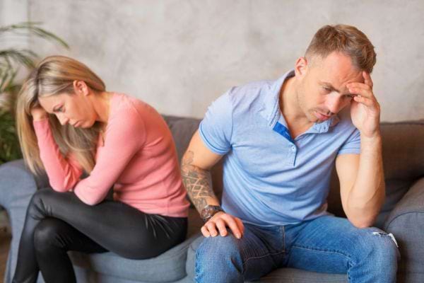 Couple assis sur un canapé, l’air triste et tendu.