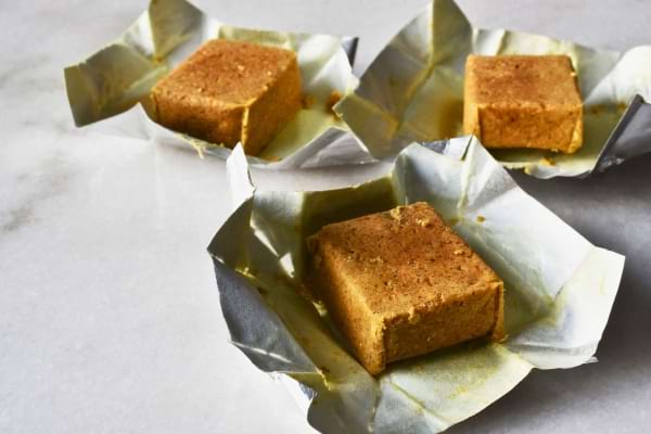 Trois cubes de bouillon sont posés sur leur emballage ouvert sur un plan de travail en marbre.